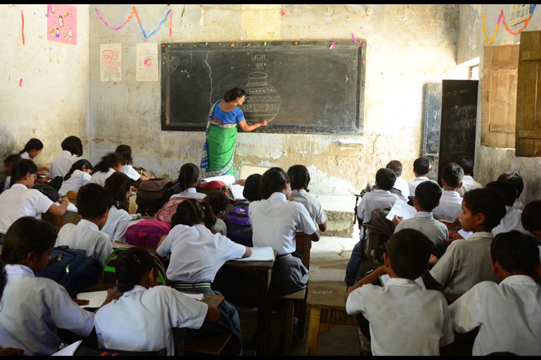 Indian teacher guiding school students in a computer-free classroom